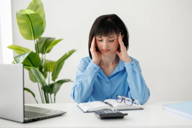 Çok çalışan genç iş kadını masajı tapınaklarda, bilgisayarın başında dizüstü bilgisayarla oturduktan sonra baş ağrısı çekiyor, gözleri kapalı yorgun bir kadın başını okşuyor, acıdan kurtuluyor.
