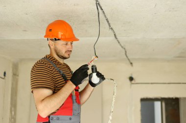 Üniformalı elektrik, koruyucu eldivenler ve tornavida ile elektrik voltajının kontrol edilip ölçülmesi. Yeni binadaki kabloları voltaj dedektörüyle inceliyorum..