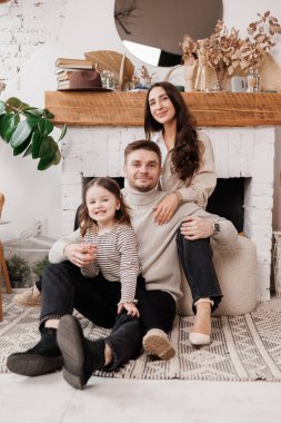 Mutlu aile günleri. Genç, sevgi dolu ebeveynler, anne ve baba, evde İskandinav oturma odasında eğlenen, kucaklayan ve gülen sevimli küçük kız çocuklarını gıdıklıyor. Ebeveynlik ve çocukluk kavramı..