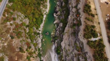 Zümrüt suyu Moraca nehri, hareketli arabalarla asfalt yolu ve Karadağ 'ın yürüme yolu olan kayalık bir kanyonun insansız hava aracı görüntüsü. Yazın canlı yeşil bitki örtüsü. Popüler seyahat hedefi.
