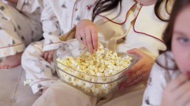 Aile günü. Tanımlanamayan bir anne, çocuklar rahat pijamalarıyla evde film izlerken cam kaseden patlamış mısır alıyor. Annem Noel tatilini çocuklarla kanepede geçirir. Mutlu çocukluk.