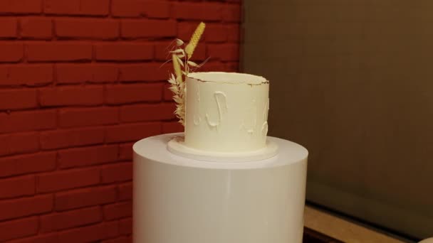 素朴なスタイルで1層の誕生日ホワイトケーキを祝い レセプションレストランで立っているドライ小麦スパイシーツとバニラクリームのアイシングを飾ります 結婚式 記念パーティー イベントでのケータリングサービス — ストック動画