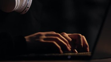 Genç bilgisayar oyuncusunun gözlüklü, kulaklıklı, dizüstü bilgisayarda yazan, bilgisayar oyunları oynayan, esportlarını karanlık odada yapan görüntüsü. Öğrenci, sosyal medyada bilgisayar eğitimi veya iletişim kuruyor