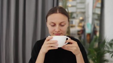 Kapalı gözlü genç bir kadın büyük bardakta taze kahve kokluyor ve içiyor, molanın tadını çıkarın. İnternetten kız alışverişi, blog yazma, e-posta kontrolü. Online eğitim. İnsanlar ve yaşam tarzı kavramı.