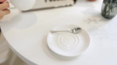 Kahve molası. Genç bir kadın elinde sütü kapalı bir fincan kahve ile evde dizüstü bilgisayarla boş vakit geçirmekten hoşlanıyor. Kendine güveni olan bayan yeni başlayan yaratıcı serbest yazar uzak bir iş yerinde cappuccino tatma gevşetir.