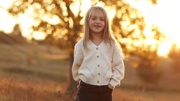 子どもの日 愛らしい小さな子供の白人少女の肖像画5 6年は笑顔で 秋の夕暮れのライトで彼女の手を交差させた手でカメラを見ます 秋の休日のレジャー活動 — ストック動画