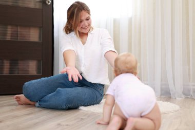 Genç anne ve kız, oğlu evde eğleniyor. Güzel anne yeni doğmuş bebeğini fırlatır ve yakalar. Çocukluk kavramı, yeni hayat, ebeveynlik. Anneler Günü.