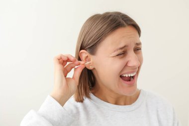 Genç bir kadın tek kullanımlık pamuk tomurcuğu, pamuk çubuğu, kulak kirini temizlemek için beyaz arka planda tutmaktan hoşlanıyor. Kişisel hijyen ve bakım ürünleri. Kulak hastalıklarının önlenmesi. Sülfür dolgusu kaldırma