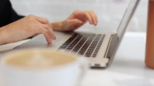 裁剪后 女性的手可以在自助餐桌上输入笔记本电脑键盘 身份不明的女企业家自由撰稿人在咖啡店或家中与计算机在线远程工作 喝一杯咖啡 — 图库视频影像