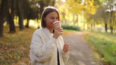 Kısa saçlı genç bir kadın, soğuk bir sonbahar günü, sonbahar parkında sıcak içecek, kahve ya da çay içmekten zevk alır. İçecek bir şeyler. Mutlu sıfır israf yaşam tarzı konsepti.