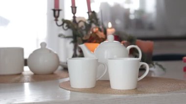 Kahvaltılık aile çay saati. İki beyaz seramik bardak, çaydanlık ve yanan mumlarla dolu bir şamdan. Tanınmayan kadın ve erkek sıcak bir içecekle el ele tutuşur..