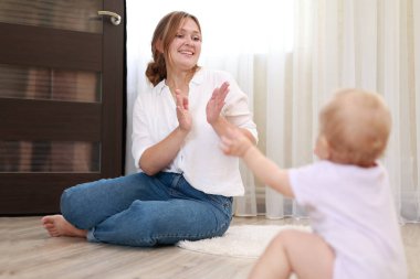 Genç anne ve kız, oğlu evde eğleniyor. Güzel anne yeni doğmuş bebeğini fırlatır ve yakalar. Çocukluk kavramı, yeni hayat, ebeveynlik. Anneler Günü.