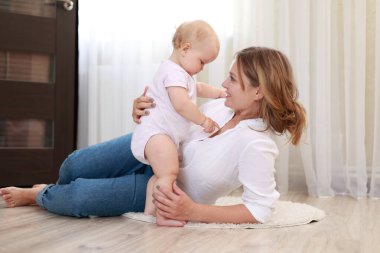 Genç anne ve kız, oğlu evde eğleniyor. Güzel anne yeni doğmuş bebeğini fırlatır ve yakalar. Çocukluk kavramı, yeni hayat, ebeveynlik. Anneler Günü.