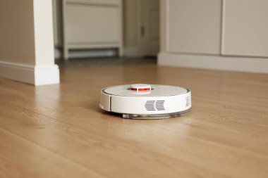 Modern kablosuz otonom robot elektrikli süpürge oturma odasını temizliyor. Akıllı oto itişli beyaz temizlik robotu ahşap zemini yıkıyor. Uzaktan kumandalı ev aletleri