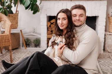 Mutlu, genç aşık çift, İskandinav tarzı evinde sevgililer gününü kutlarken nazikçe sarılıp gülümsüyor. Erkek ve kadın birlikte vakit geçirmekten zevk alıyor, randevularda dinleniyorlar.