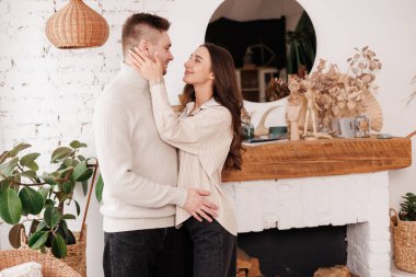 Mutlu, genç aşık çift, İskandinav tarzı evinde sevgililer gününü kutlarken nazikçe sarılıp gülümsüyor. Erkek ve kadın birlikte vakit geçirmekten zevk alıyor, randevularda dinleniyorlar.