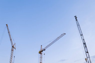 İnşaat alanı. Alacakaranlık mavisi arka planda birçok kule vinci var. Çok katlı konut ve ticari gayrimenkul inşaatı. Yeni inşaat endüstrisi. İpotek kavramı.