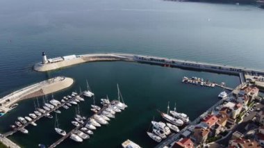 Lustica Körfezi, Adriyatik denizi, Karadağ 'ın havadan görünüşü. Binaların üst manzarası, liman limanı, demirli tekneler, yatlar ve deniz feneri, dağların arka planında. Yeni modern lüks tatil köyü.