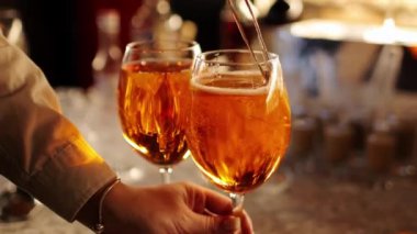 Barmen tezgahta iki bardak Aperol spreyi hazırlıyor, taze portakal dilimleri ekliyor. Tipik alkollü İtalyan içeceği, Prosecco marka beyaz şarap ve buzlu aperatif.