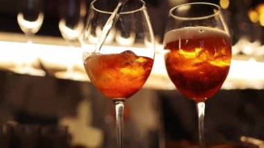 Barmen tezgahta iki bardak Aperol spreyi hazırlıyor, taze portakal dilimleri ekliyor. Tipik alkollü İtalyan içeceği, Prosecco marka beyaz şarap ve buzlu aperatif.