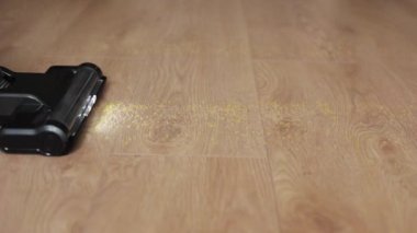 Tanımlanamayan bir kadının kablosuz elektrik süpürgesini plastik zeminden mutfak çöplerini temizlemek için kullanırken çekilmiş videosu, kadın bacakları geçiyor. Modern ev aletleri