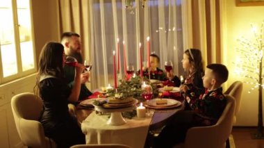 Evde aile Noel yemeği. Mutlu anne, baba ve üç çocuk köknar dallarıyla süslenmiş festival masasında oturup Noel arifesini, 2025 'i ve tatil sezonunu birlikte kutluyorlar.