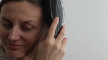 Saç fırçasıyla saçlarını taradıktan sonra doğal kısa saçlarında statik elektrik olan genç bir kadın. Elektrikli saçlı kız. Yapışkan saçlar. Güzellik tedavisi.