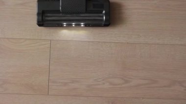 Oda hizmetleri. Tanımlanamayan kadın kablosuz elektrik süpürgesi kullanıyor mutfak çöplerini aydınlatmak için, lamine zeminden gelen gevşek inlemeler. Modern ev aletleri.