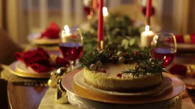 Noel şenlikli cheesecake süslenmiş biberiye dalları, yaban mersini ve beyaz toplar altın tabakta. Ev yapımı kırsal tatlı. Kamera hareket ediyor. Yeni yıl partisini evde kutluyoruz..