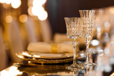 Tabaklı lüks masa, yüzüklü peçete, kristal şarap bardakları ve ayna masasında altın çatal bıçak restoranda romantik bir akşam yemeği için, Bokeh. Noel, 2026 yılbaşı yemeği. Düğün, doğum günü