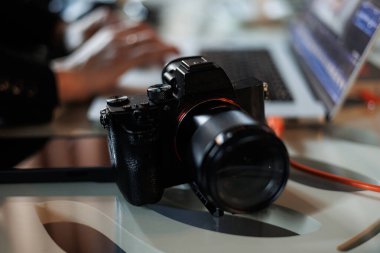 Dizüstü bilgisayarı ve fotoğraf makinesi olan çalışma alanı. Tanımlanamayan kadın fotoğrafçı çalışıyor, bilgisayardaki DSR kamerasından fotoğrafları iş yerindeki kabloyla gönderiyor. Yaratıcı sanatçı yaşam tarzı.