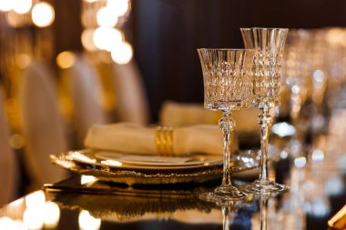 Tabaklı lüks masa, yüzüklü peçete, kristal şarap bardakları ve ayna masasında altın çatal bıçak restoranda romantik bir akşam yemeği için, Bokeh. Noel, 2026 yılbaşı yemeği. Düğün, doğum günü