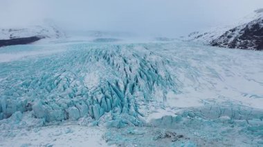 İzlanda 'daki görkemli buzlu mavi buzulların hava manzarası. Buzul Skaftafell 'in, Vatnajokull Ulusal Parkı' nın, Jokulsarlon Buzul Gölü 'nün üstünde. Grönland 'da karla kaplı uçurumlarda uçan FPV dronu