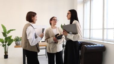 Üç profesyonel iş kadını dizüstü bilgisayarla kampanyayı tartışıyor yeni fikirler, iş projesi, modern ofiste iş çözümleri, masanın yanında ve geniş pencerenin yanında. Takım çalışması, iletişim, işbirliği