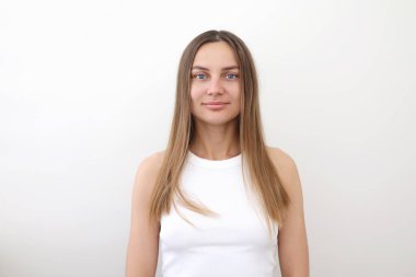 Mükemmel pürüzsüz tenli, beyaz arka planda izole edilmiş, gülümseyen ve kameraya bakan genç, doğal güzellikte esmer bir kadının portresi. Yüz ve cilt bakımı, estetik cerrahi, kozmetoloji, kozmetik