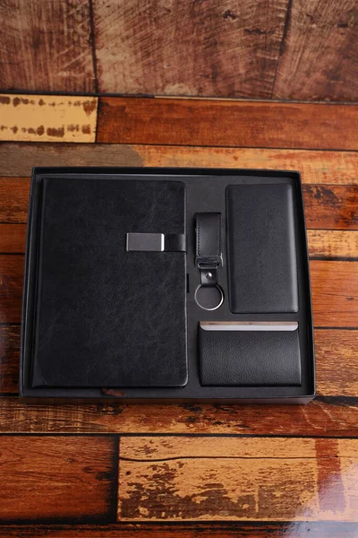 Customized corporate gift box mock up image, Personalized power bank with mobile stylus, hard cover Customized notebook and id card holder,  Customized leather keychain , Black color concept corporate gift box photography