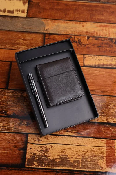 corporate gift box wallet and steel pen, open top view on the wooden table