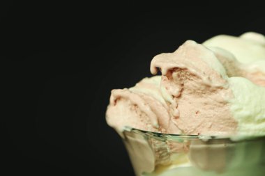Strawberry ice cream in a bowl on a black background.