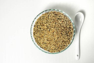 Beyaz arka planda bir kasede organik susam tohumları.