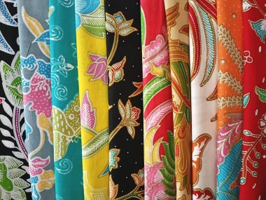 Bali pazarında satılık renkli kumaş elbiseler. Bali Endonezya 'daki bir pazarda sergilenmekte olan çok sayıda parlak baskılı kumaş örneği