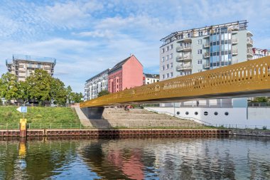 Berlin, Germany - September 23, 2022: Sunbathing lawn at Nordhafen harbor with the new bridge Golda-Meir-Steg over the Berlin-Spandau shipping cana