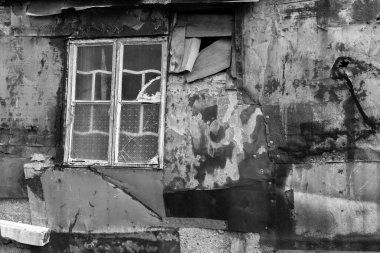Terk edilmiş evin duvarında kırık bir pencere.