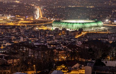 Bursa şehrinin havadan panoramik görüntüsü. Arka planda Bursaspor Stadyumu ve gece manzarası var.