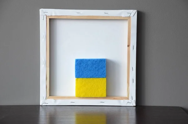 Flag of Ukraine in an art frame under an art canvas.  Awooden frame with a blue and white background.