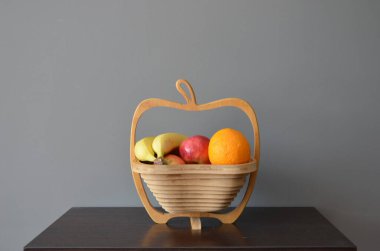 Tahta arkaplanda elmalar olan hasır sepet