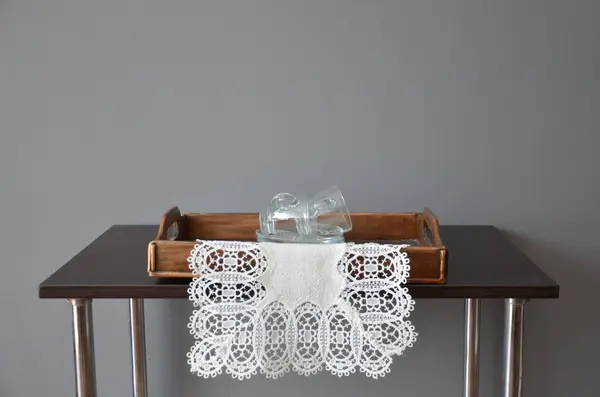 Tahta masadaki cam vazoyla sandalyede beyaz dantel..