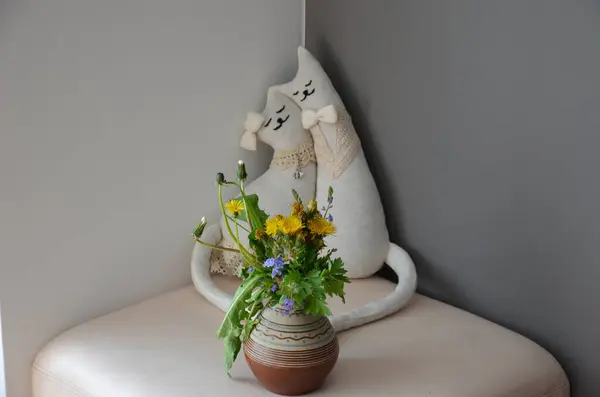 Beyaz arkaplandaki vazoda beyaz ve sarı çiçeklerin dikey görüntüsü.