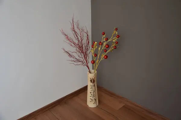 Beyaz arka planda beyaz vazo ve ahşap duvarlı kırmızı bir Noel ağacının dikey görüntüsü.