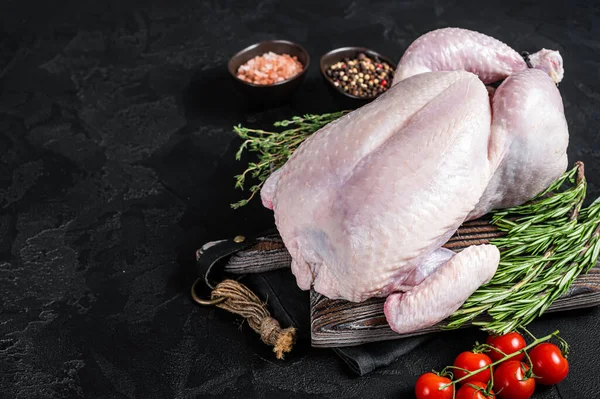 Tahta tahtada kekik ve biberiyeyle pişirilmemiş çiğ tavuk. Siyah arka plan. Üst Manzara. Boşluğu kopyala.