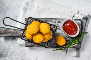 Fried potato cheese balls croquettes with tomato ketchup served in a basket. White background. Top view.